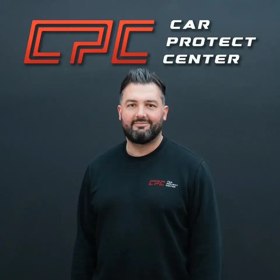 Portrait de studio d’un membre de l’équipe Car Protect Center, de face, devant le mur au logo CPC