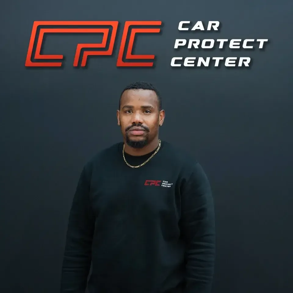 Portrait de studio d’un membre de l’équipe Car Protect Center, de face, devant le mur au logo CPC