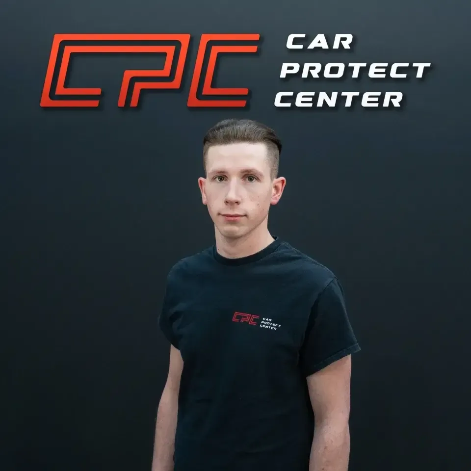 Portrait de studio d’un membre de l’équipe Car Protect Center, de face, devant le mur au logo CPC