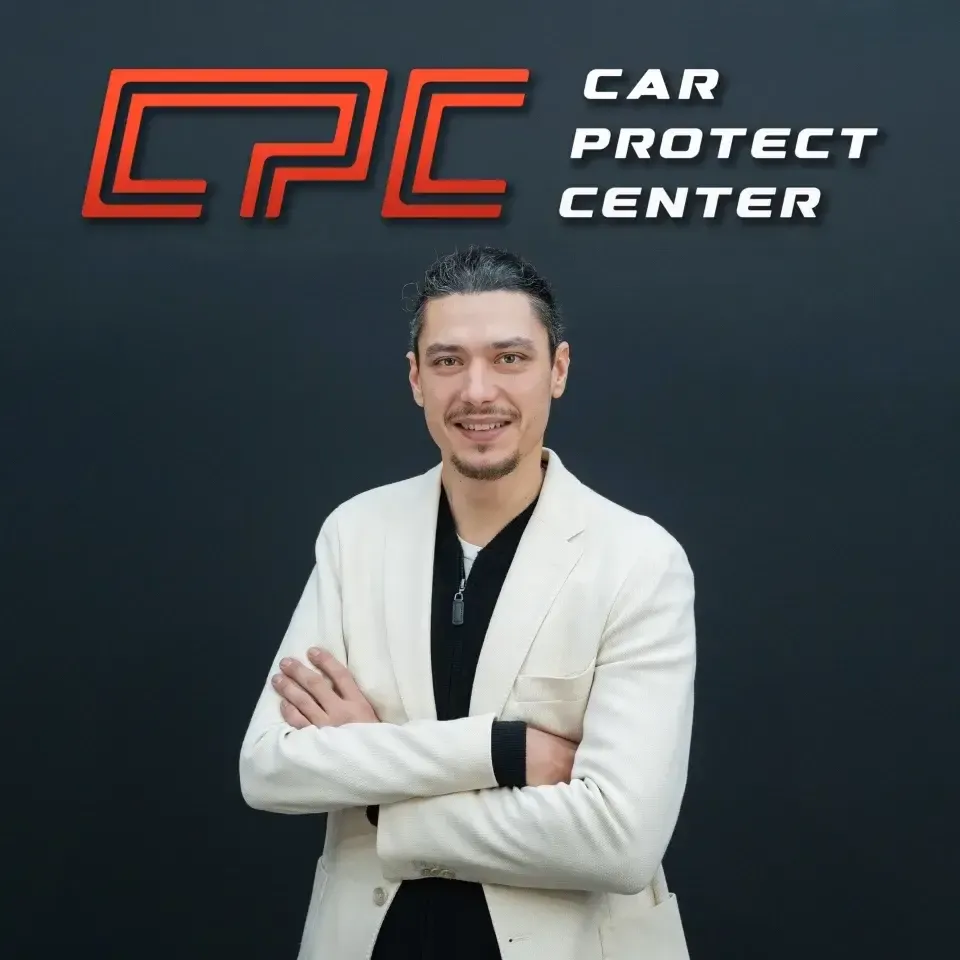 Portrait de studio d’un membre de l’équipe Car Protect Center, bras croisés, devant le mur au logo CPC