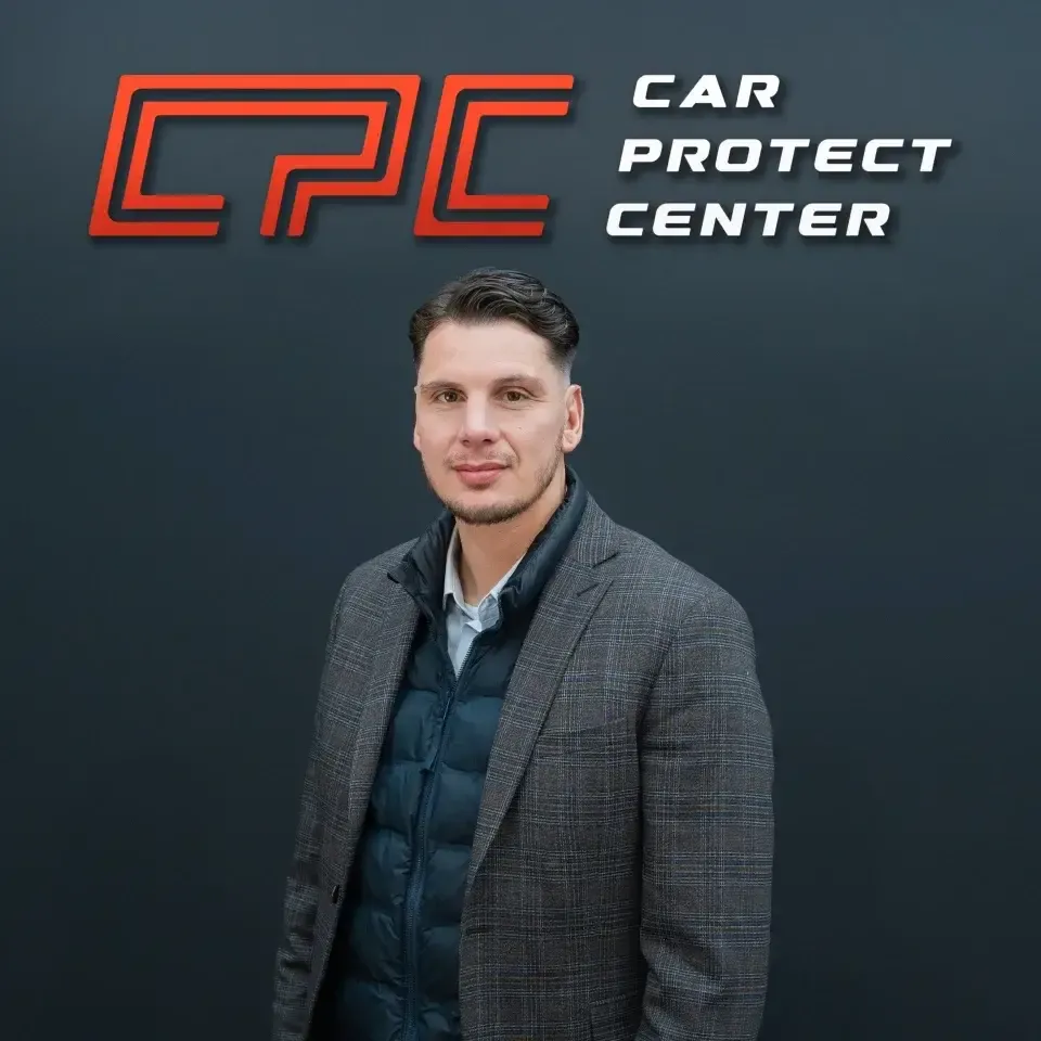 Portrait de studio d’un membre de l’équipe Car Protect Center, de trois quarts, devant le mur au logo CPC