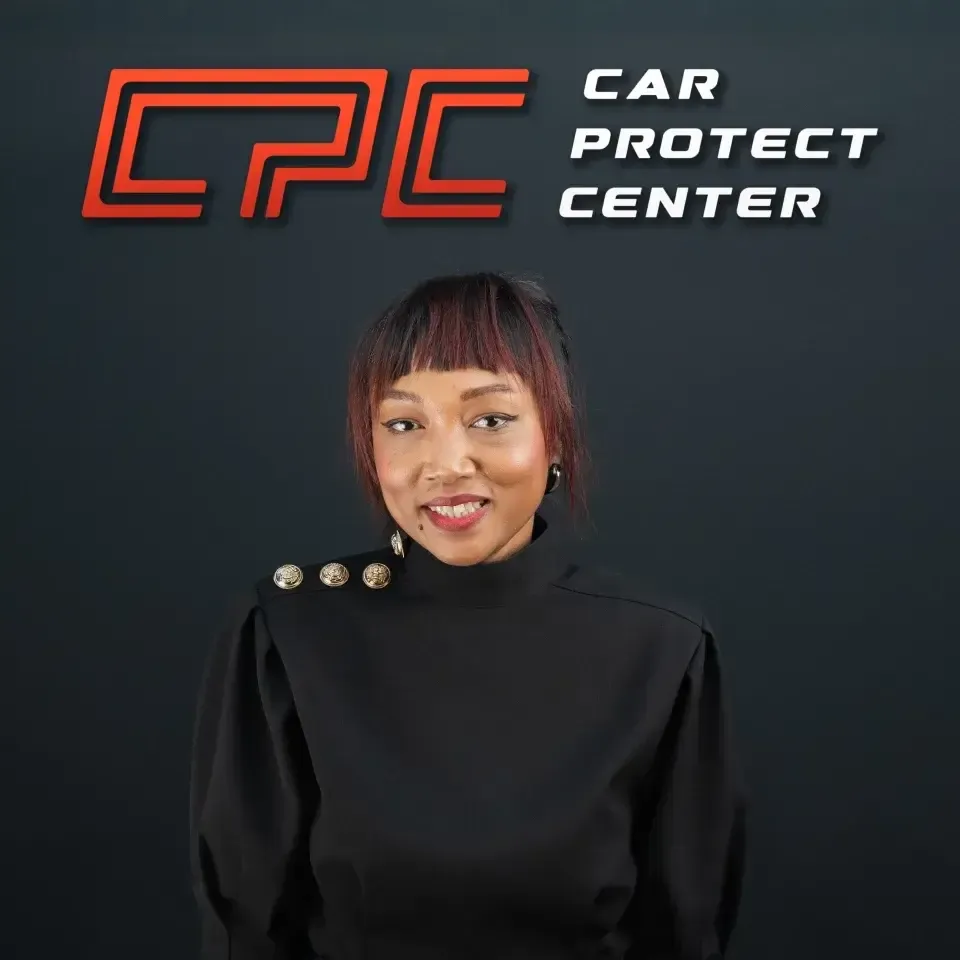 Portrait de studio d’un membre de l’équipe Car Protect Center, de trois quarts, devant le mur au logo CPC
