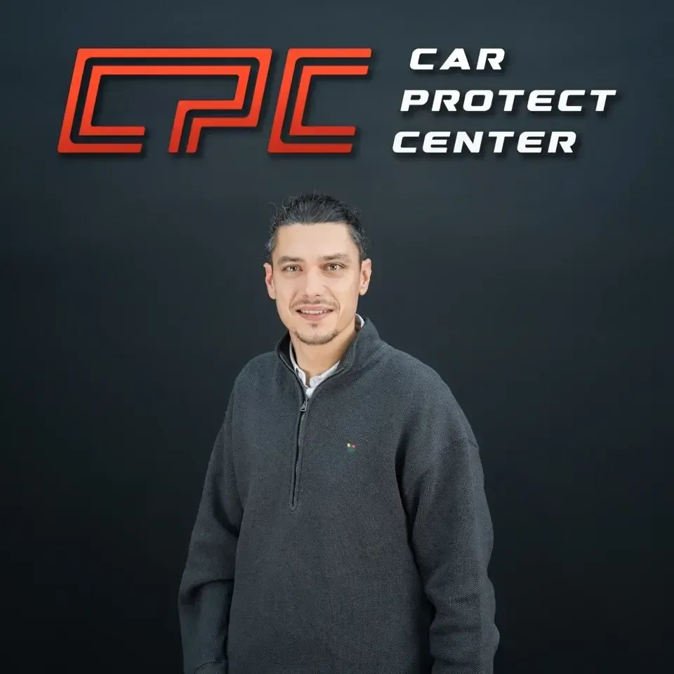 Portrait de studio d’un membre de l’équipe Car Protect Center, de face, devant le mur au logo CPC