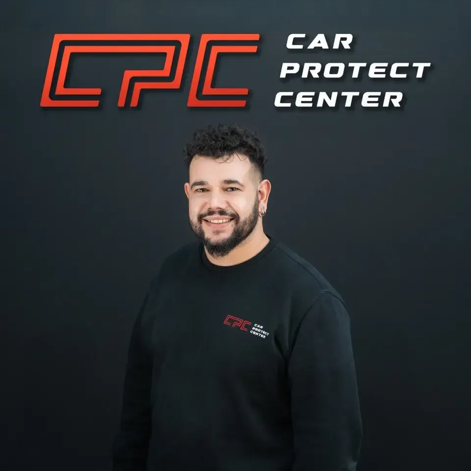 Portrait de studio d’un membre de l’équipe Car Protect Center, de face, devant le mur au logo CPC