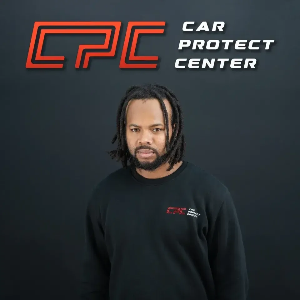 Portrait de studio d’un membre de l’équipe Car Protect Center, de face, devant le mur au logo CPC