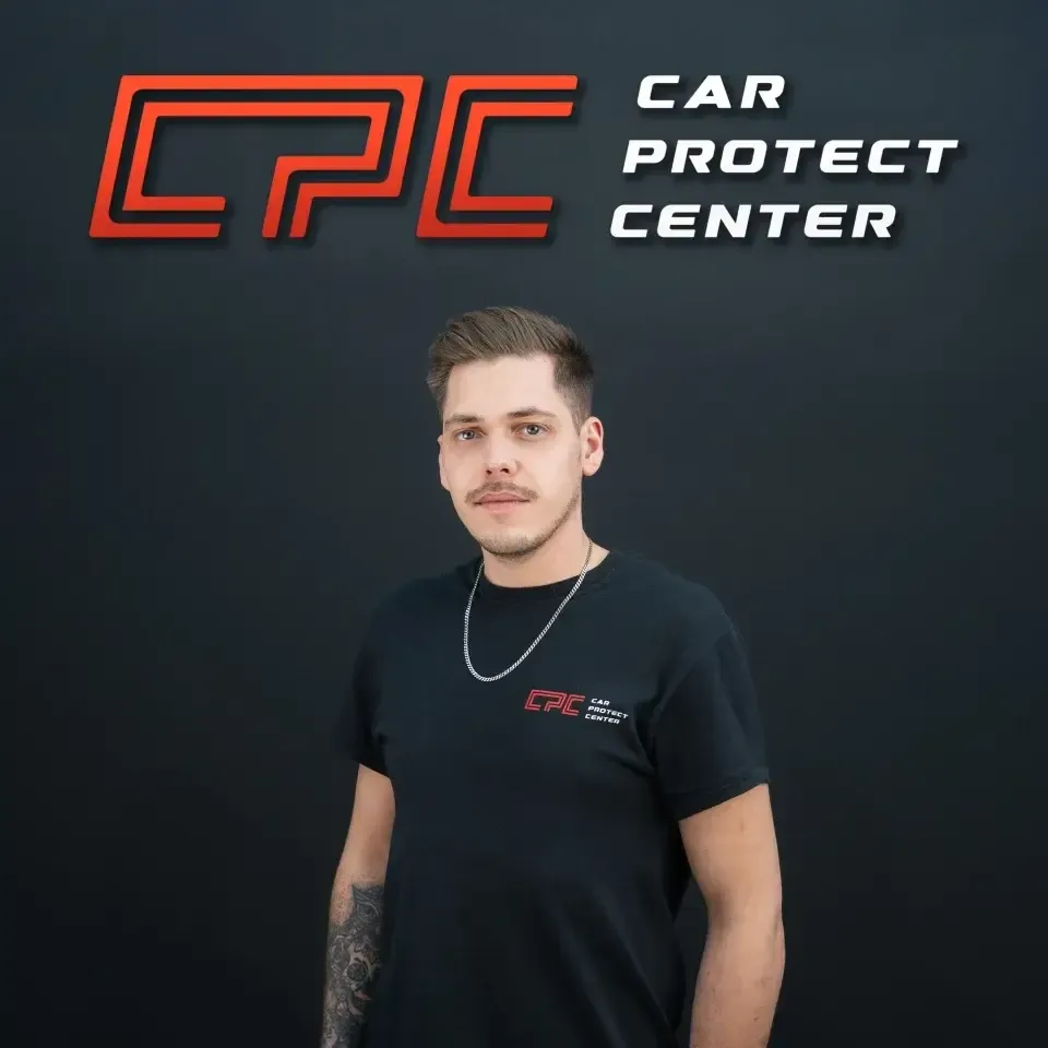 Portrait de studio d’un membre de l’équipe Car Protect Center, de face, devant le mur au logo CPC