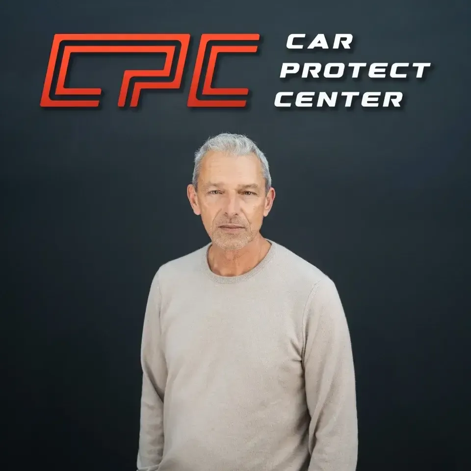 Portrait de studio d’un membre de l’équipe Car Protect Center, de face, devant le mur au logo CPC