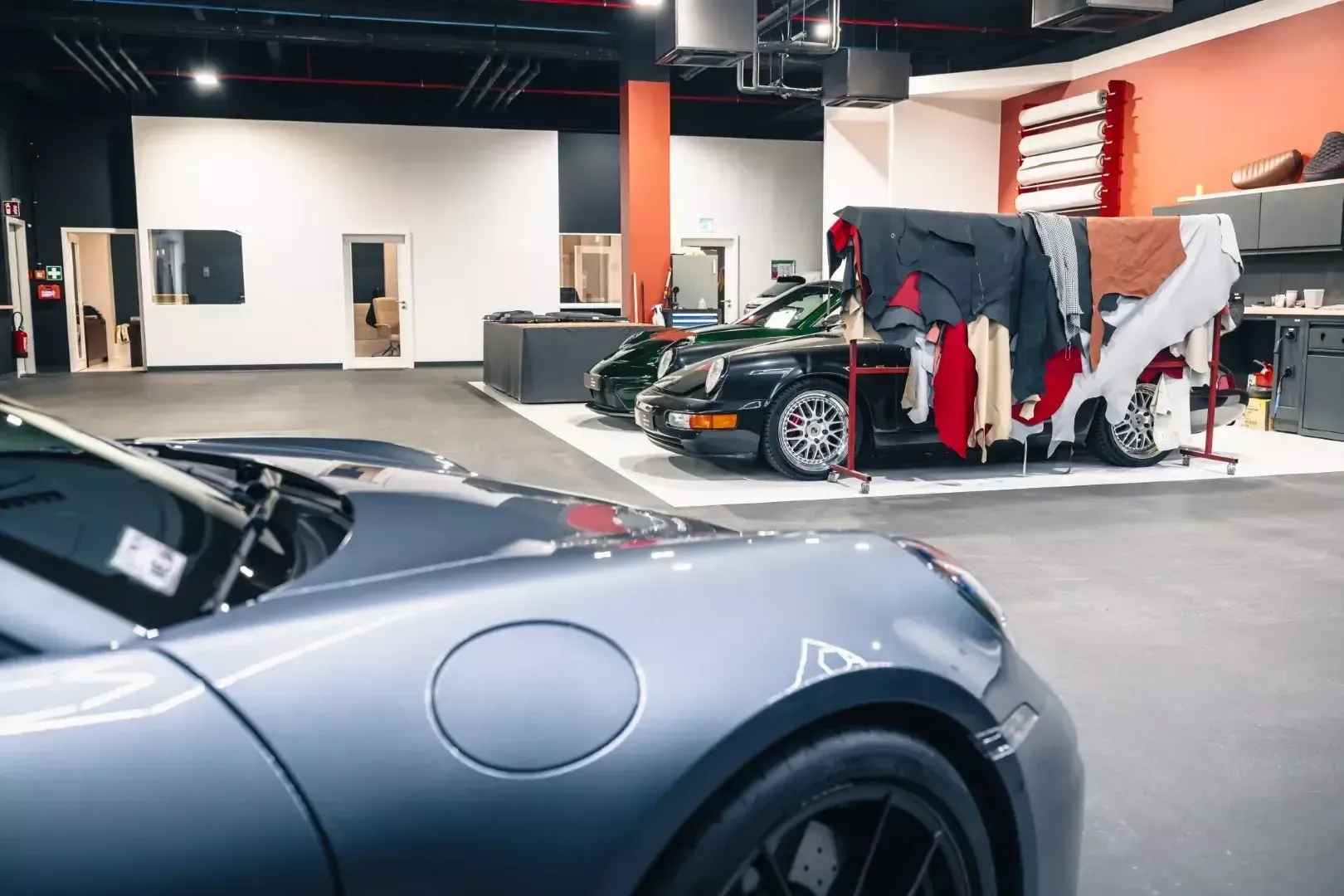 L’atelier et ses bureaux vitrés : Porsche classique en cours de sellerie et rouleaux de film de protection