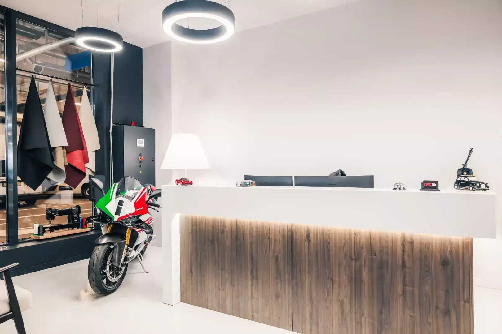 Le comptoir d’accueil en bois et blanc, avec une Ducati et des cuirs de sellerie en arrière-plan