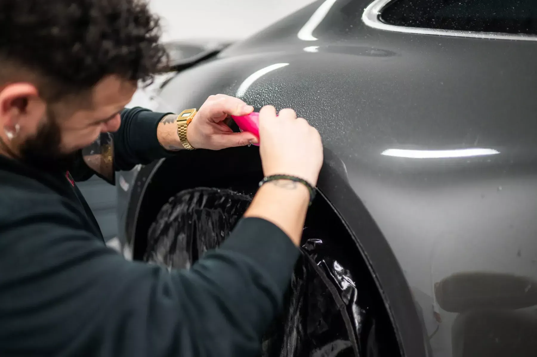 Pose à la main d’un film de protection sur l’aile d’un véhicule dans l’atelier Car Protect