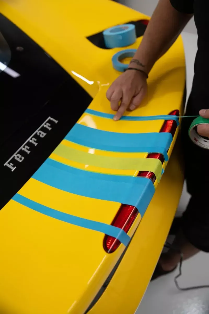 Bandes de film de protection appliquées sur la carrosserie jaune d’une Ferrari