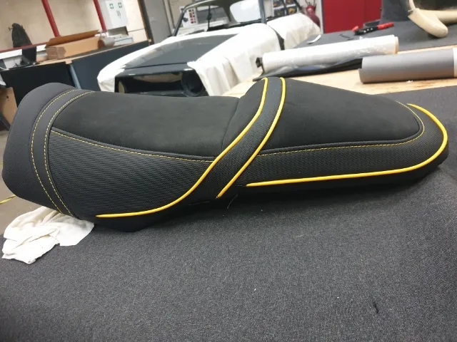 Selle de moto regarnie, posée sur le plan de travail de l’atelier